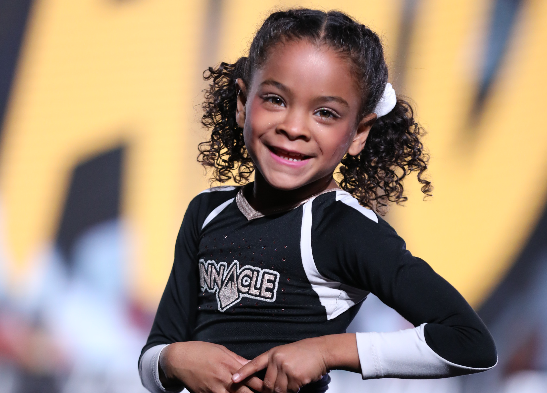 Youth cheerleader smiles at the camera during a performance